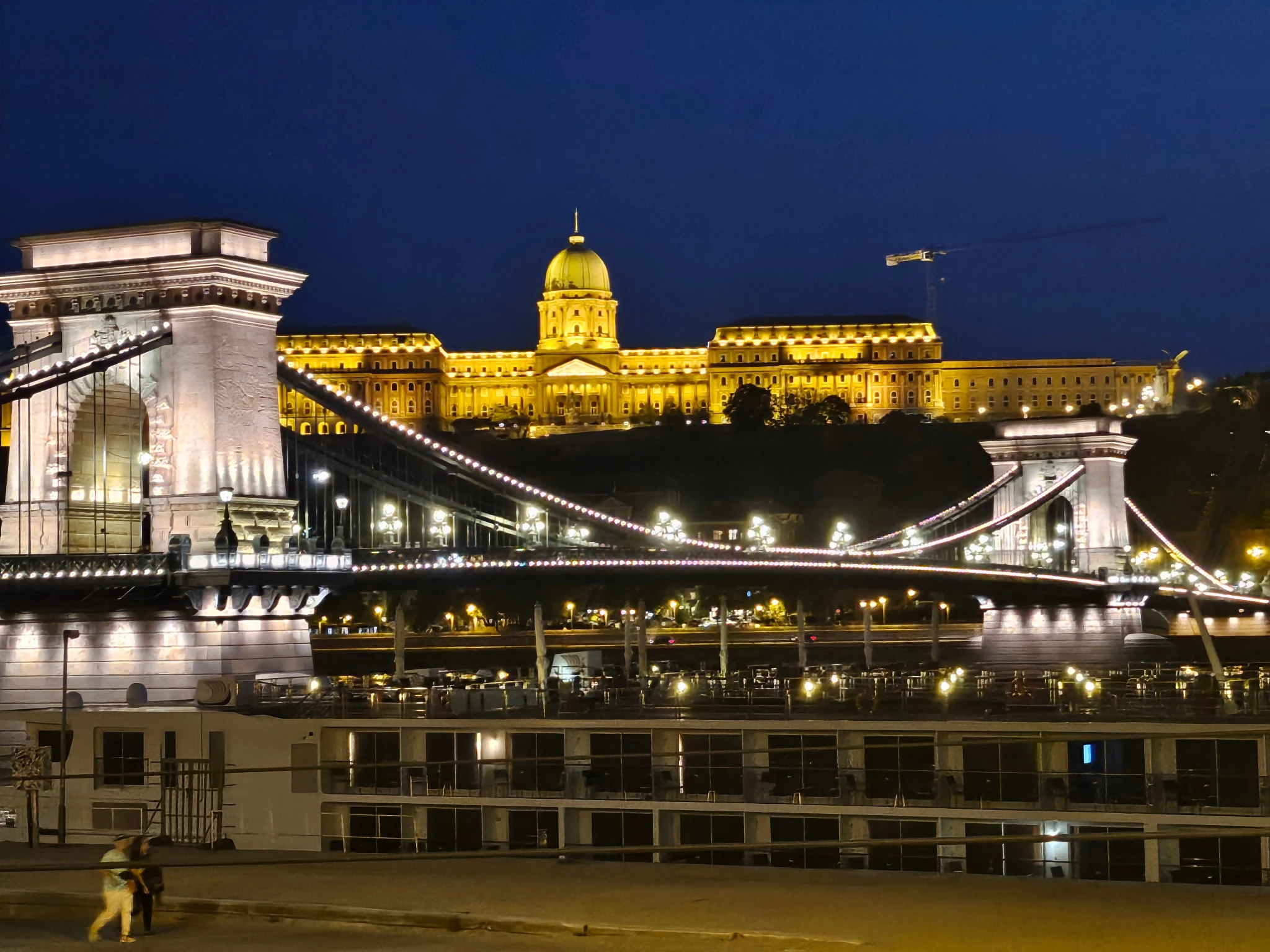 Buda Castle and the Chain Bridge illuminated across the Danube after dark.