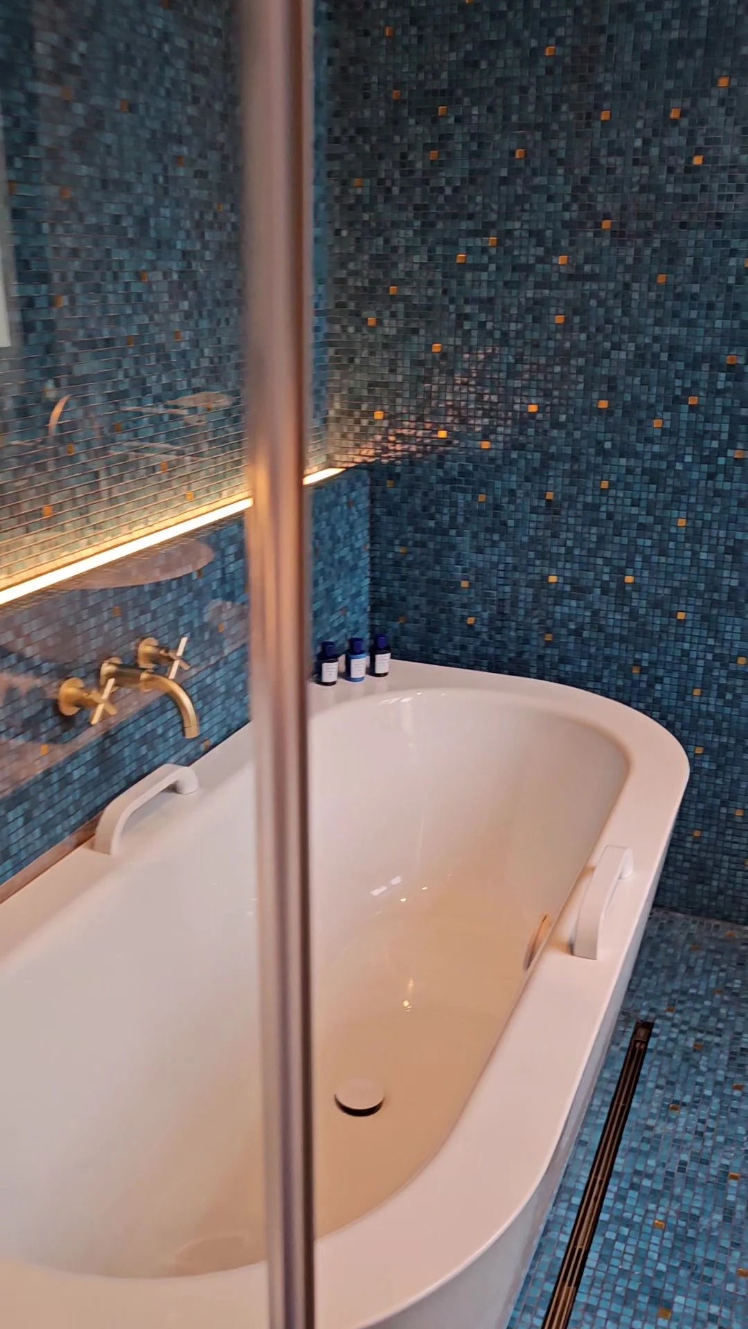 A white bathtub against blue mosaic tiles in our Matild Palace bathroom.