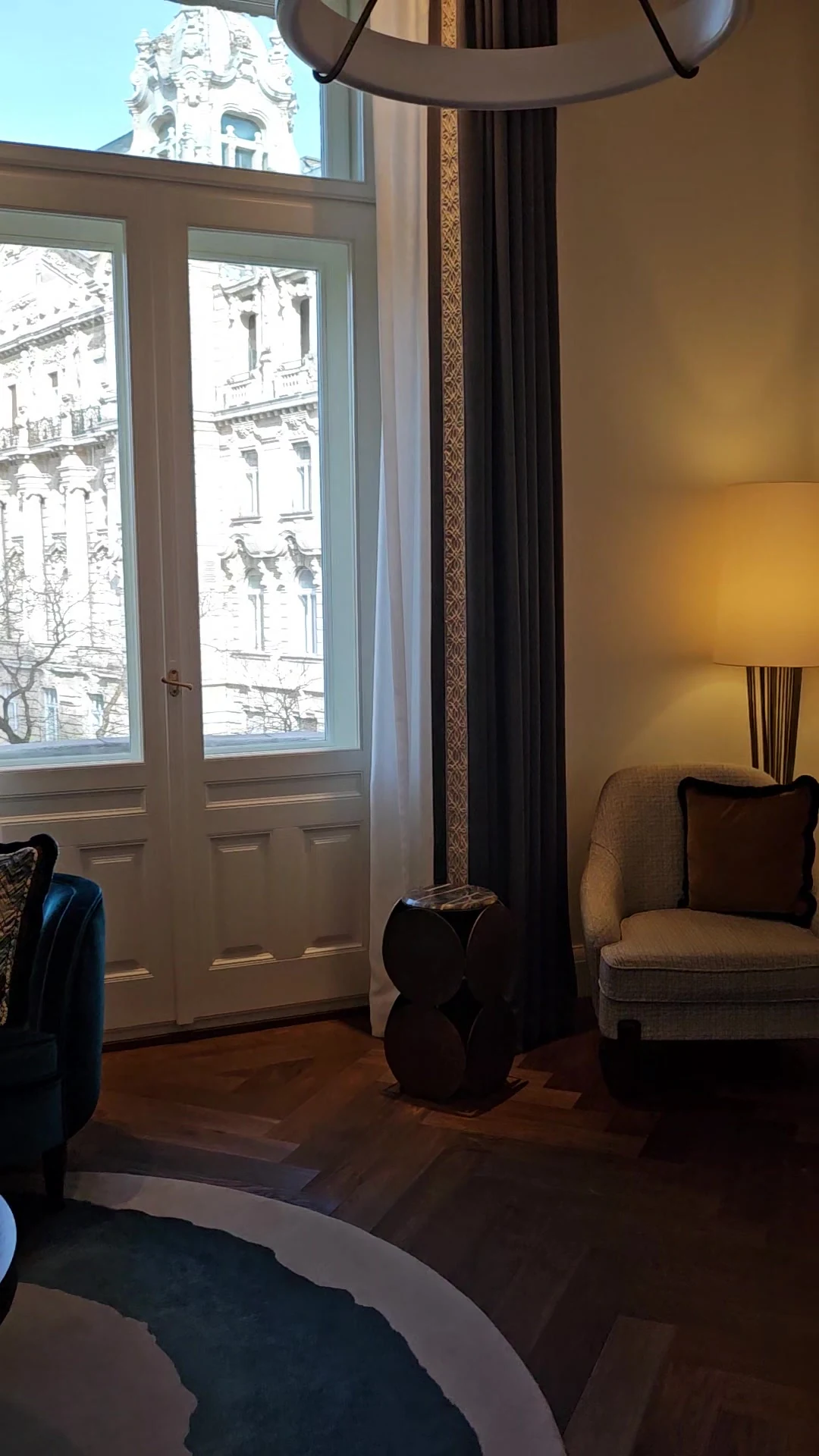 Tall windows, an armchair and patterned rug in our upgraded Matild Palace suite.