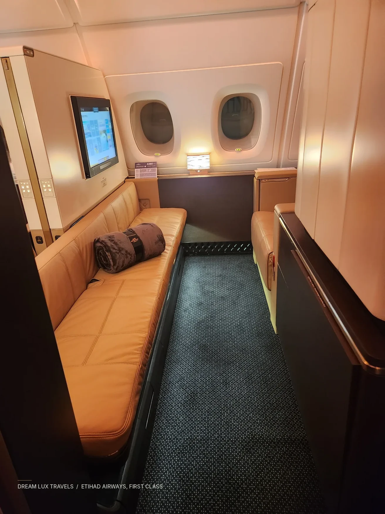Private First Class aircraft suite with warm cream upholstery and windows.