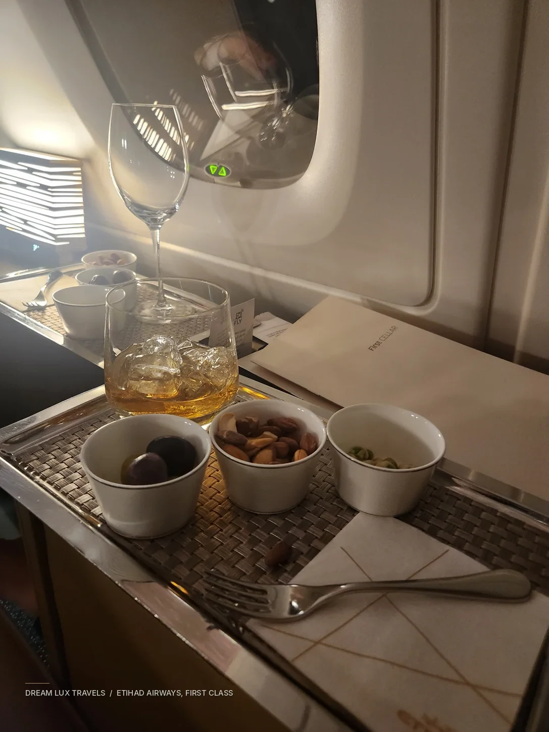 An Etihad First Class welcome drink with glassware and small dishes.