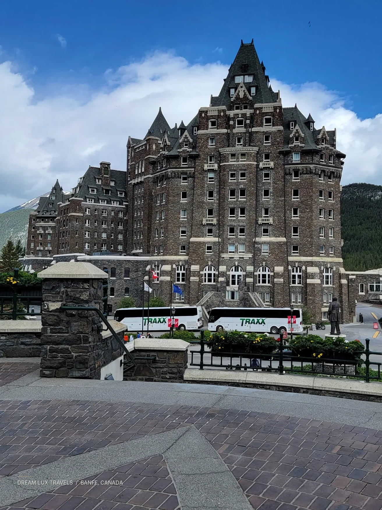 Fairmont Banff Springs stone hotel towers against a bright blue sky.
