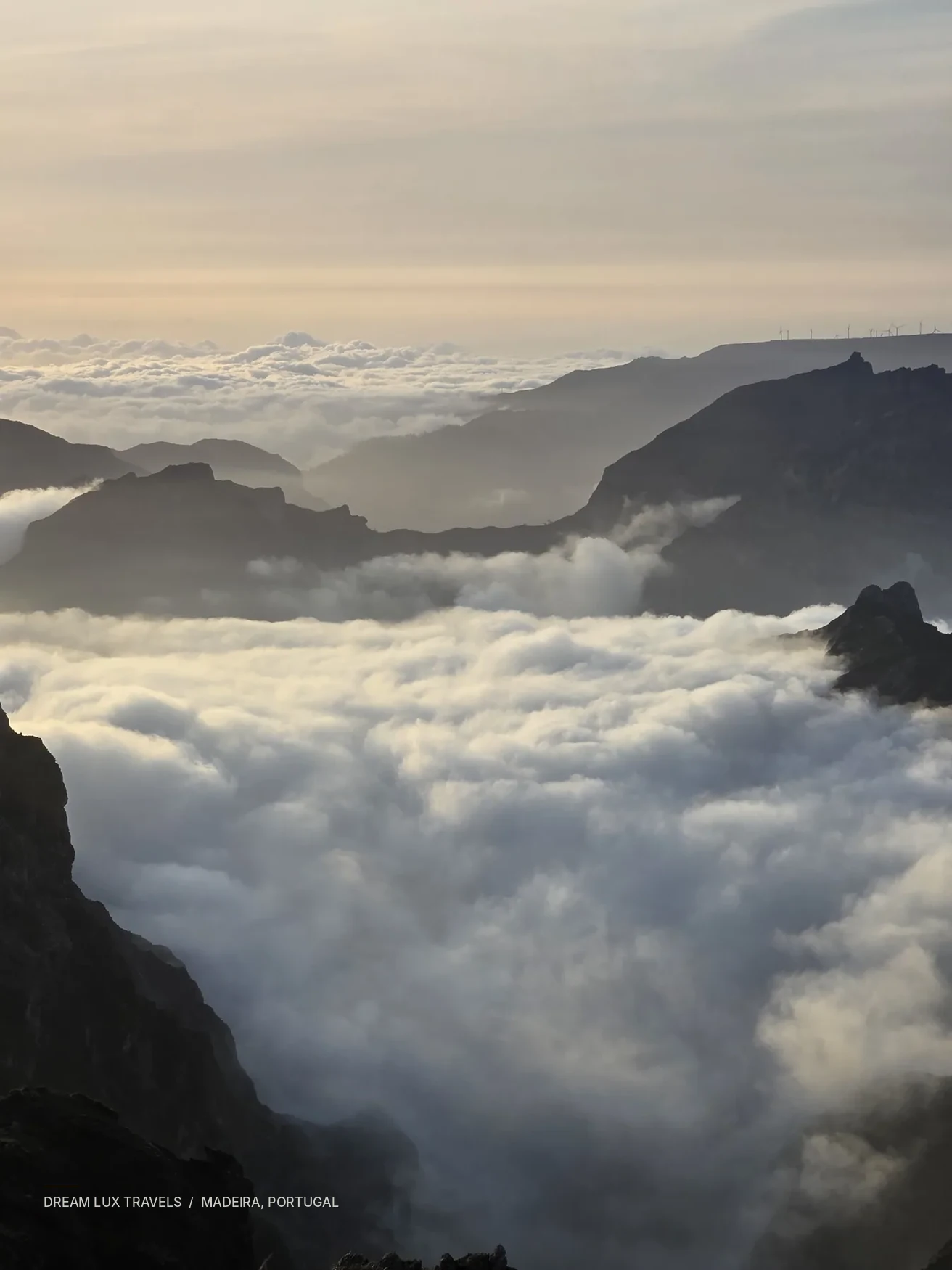 Mountain ridges rising through a sea of clouds on Madeira at golden hour.