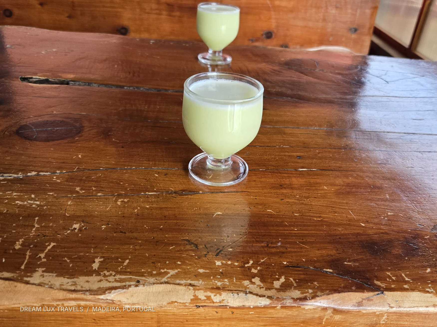 Two glasses of traditional Madeira poncha on a wooden table in a local bar.