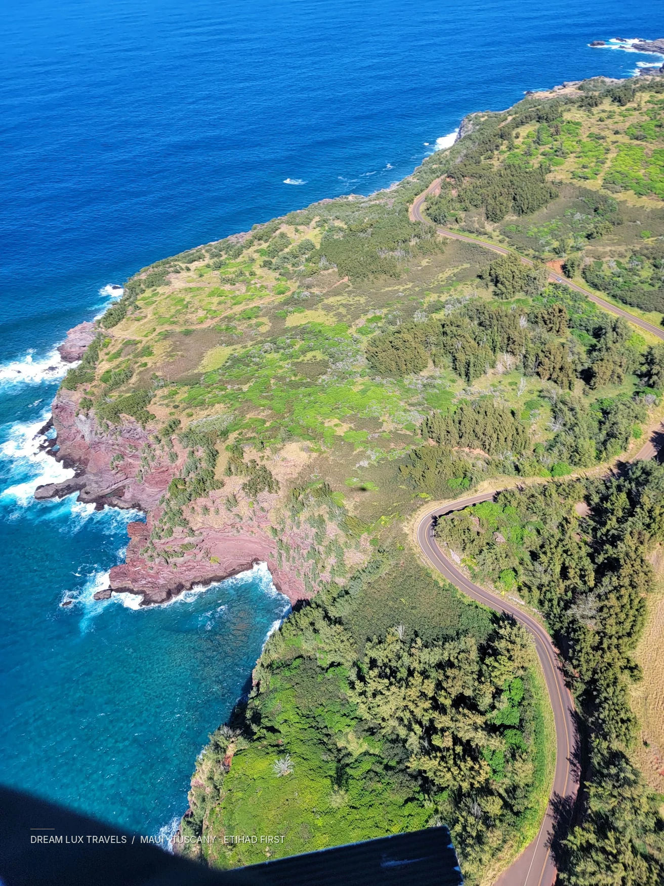Steep green Maui coastline photographed from an open-door helicopter.