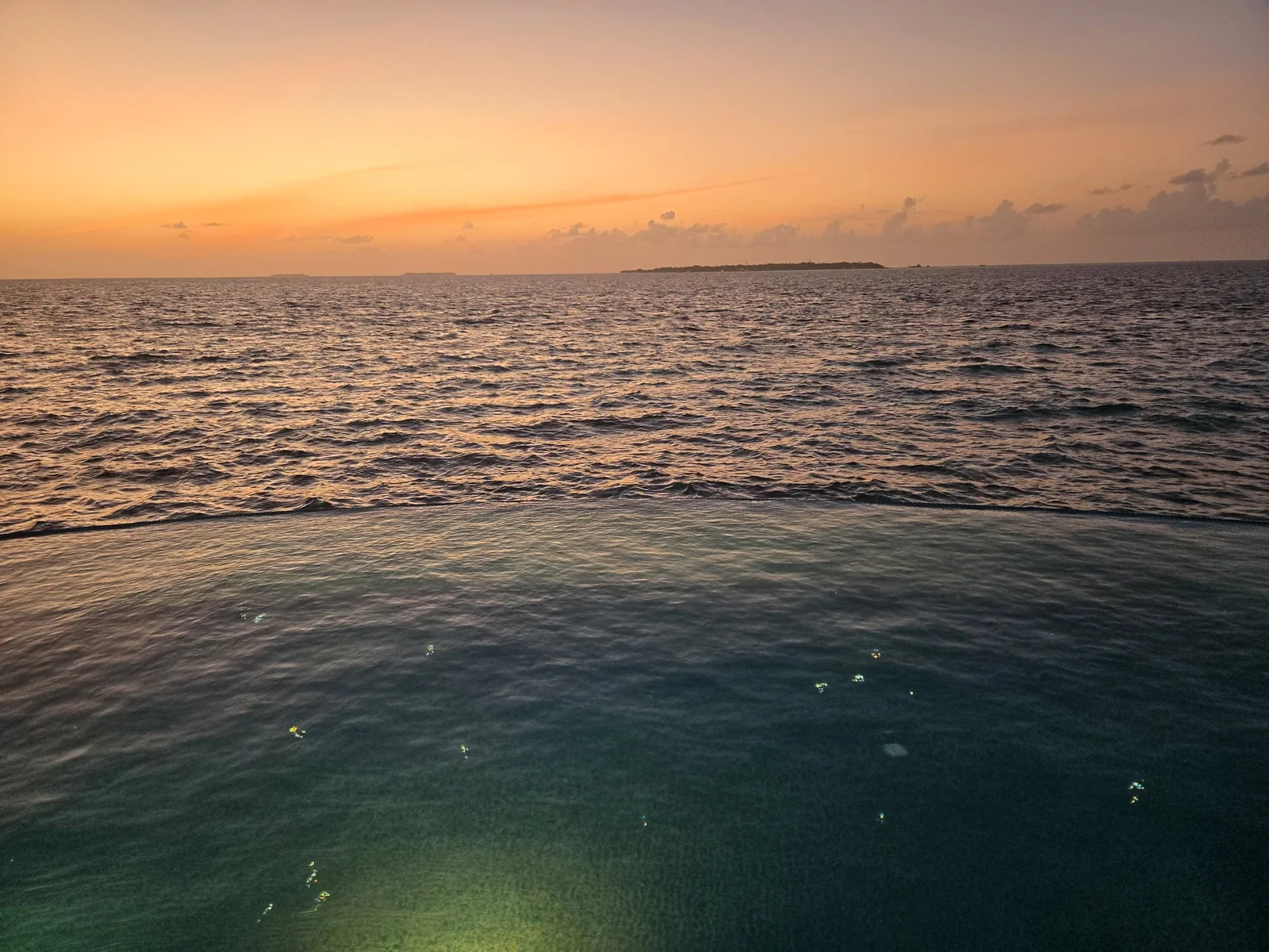 Ocean and orange-gold horizon at sunset, photographed from Milaidhoo Maldives.