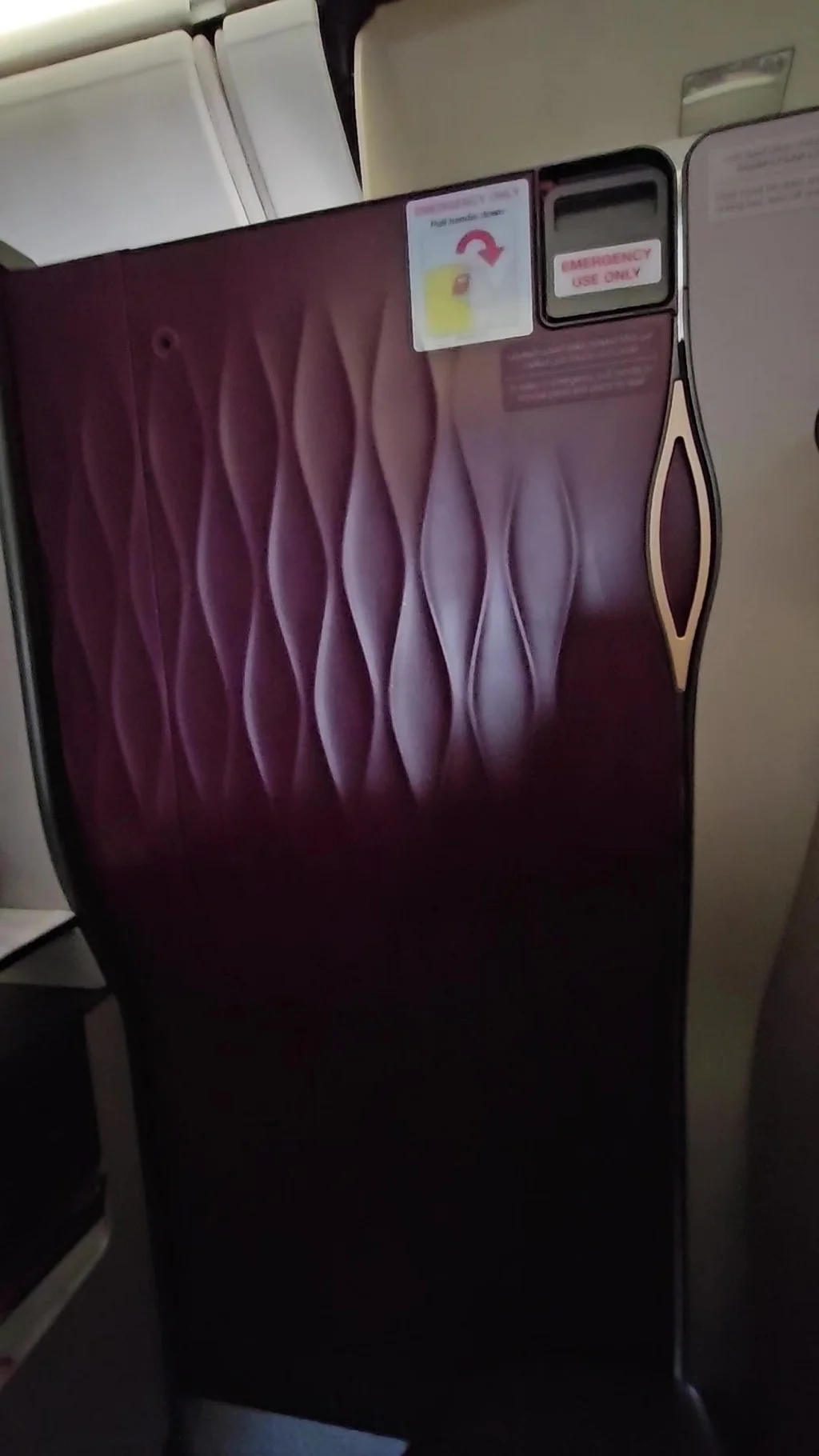 Enclosed burgundy privacy panels of a Qatar Airways Qsuite business-class seat.