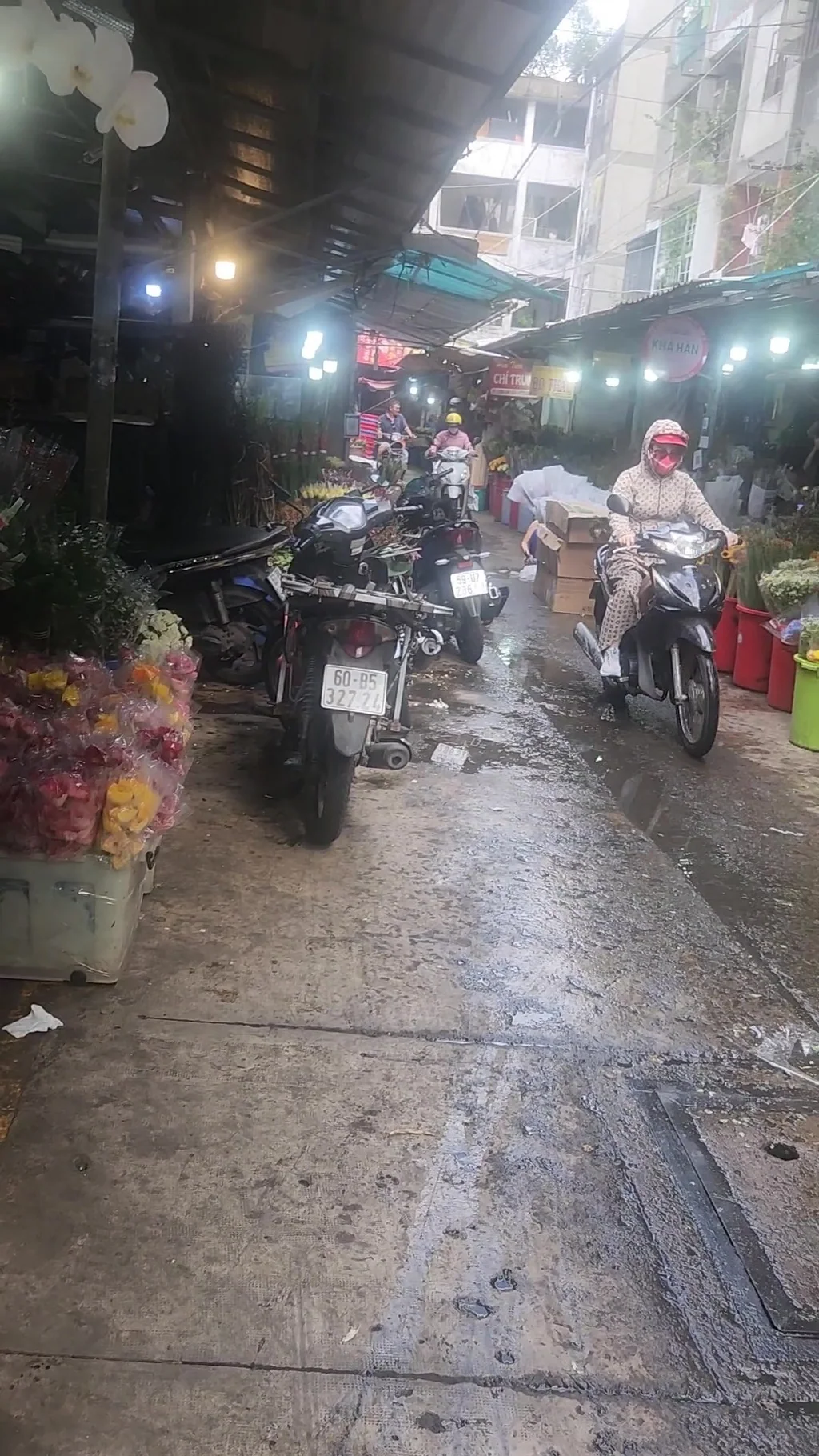 Narrow Saigon street with scooters and market activity viewed during a guided motorbike food tour.