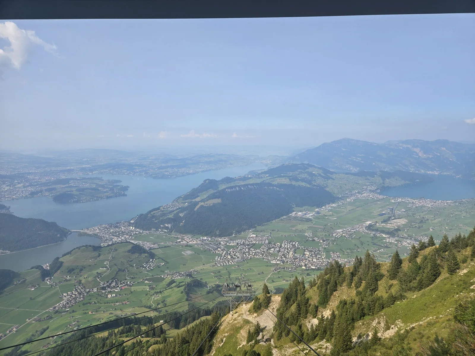 Expansive view over green fields and Lake Lucerne from the descending cable-car route near Stanserhorn.